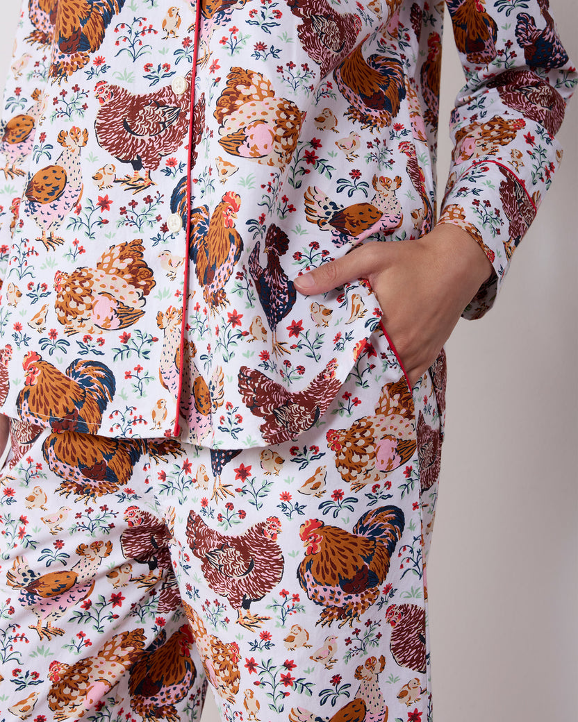Close-up of a chicken-print long pajama set showing the button-front top, piping, and side pocket.