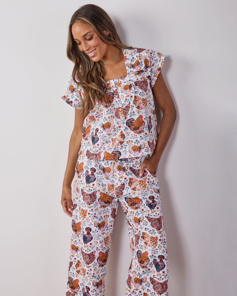 Person wearing a cropped short-sleeve top and matching pants with a colorful chicken-and-floral print.