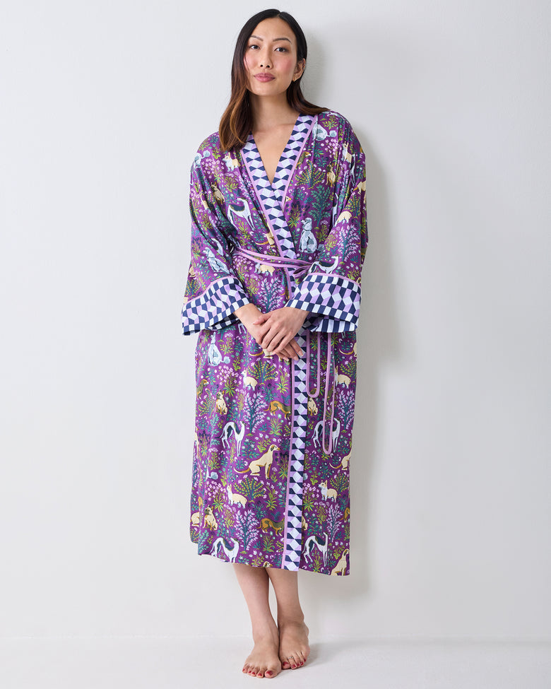 Front view of a person wearing a purple dog-and-floral print wrap robe with contrasting geometric trim, wide cuffs, and a matching belt.