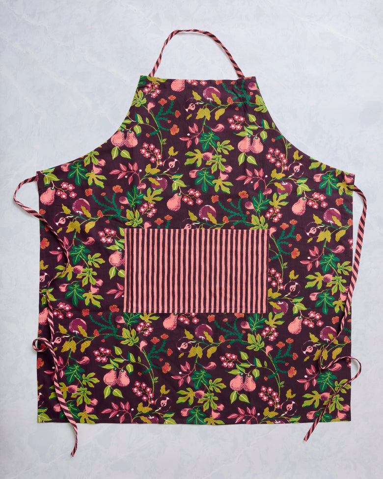 Plum Pomme & Poire apron laid flat, showing a printed fruit-and-floral pattern, adjustable neck strap, side ties, and a striped front pocket.