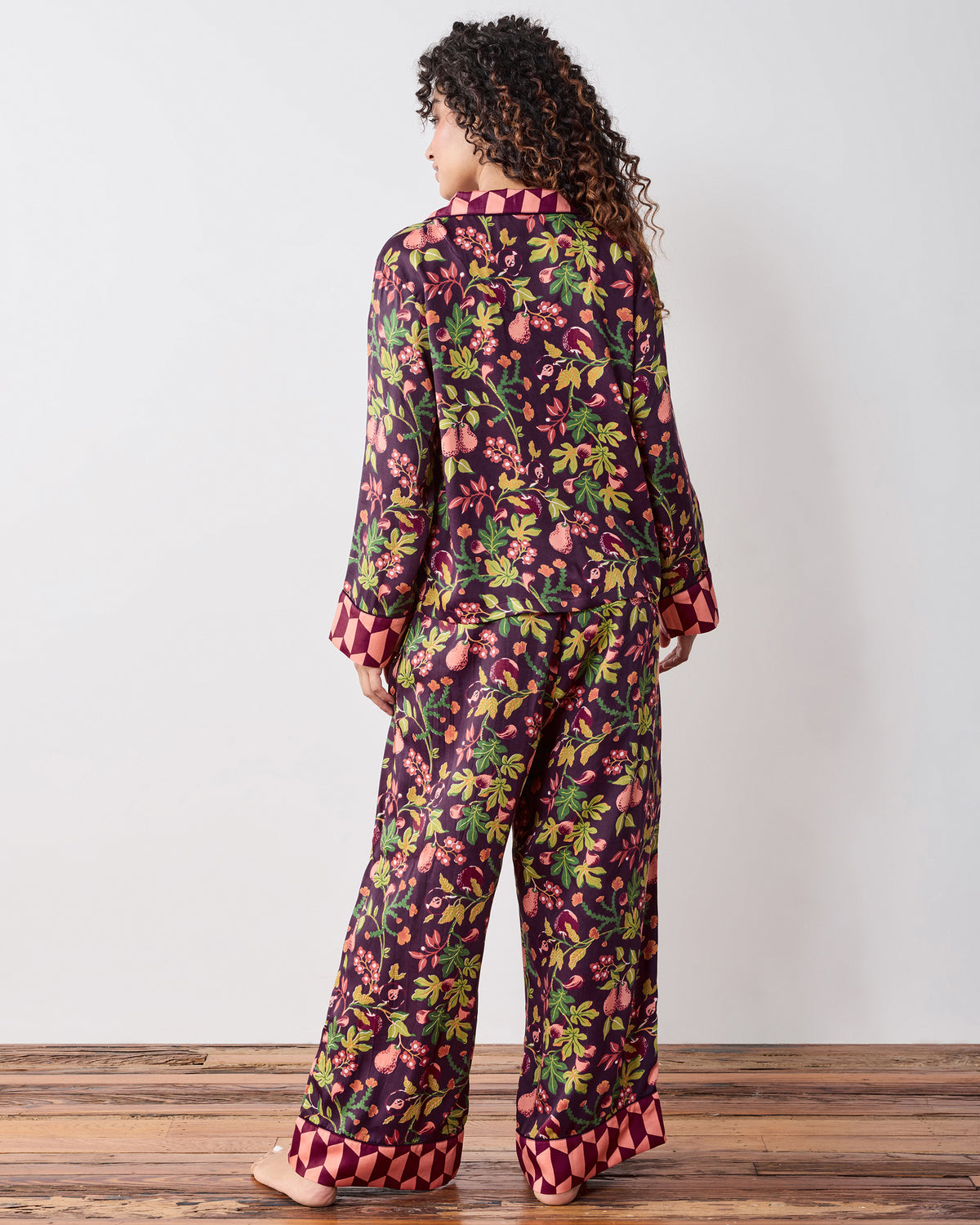 Back view of the plum Pomme & Poire Soho pajama set with a fruit-and-floral print, long-sleeve top, and wide-leg pants.