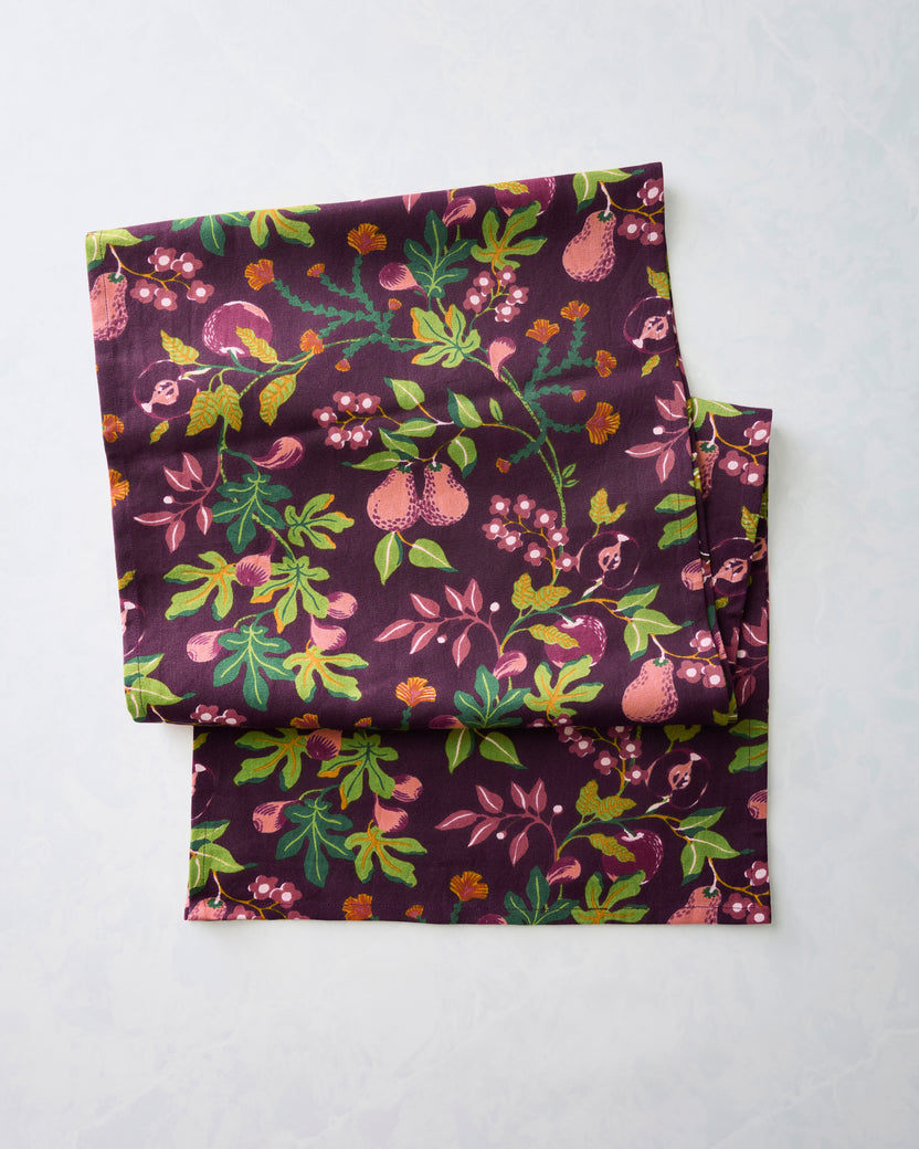 Folded Pomme & Poire table runner with a plum fruit-and-floral print.