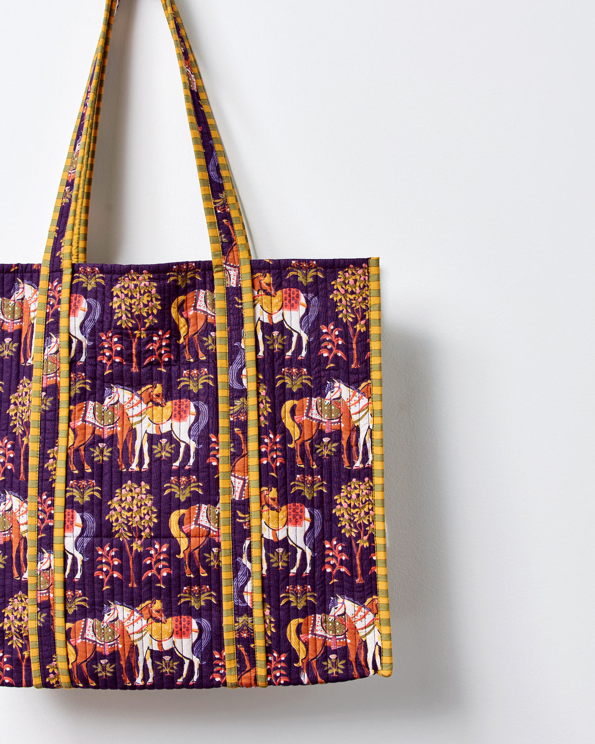 Close-up of the horse-print quilted tote bag, showing the front panel, vertical stitching, and shoulder straps.