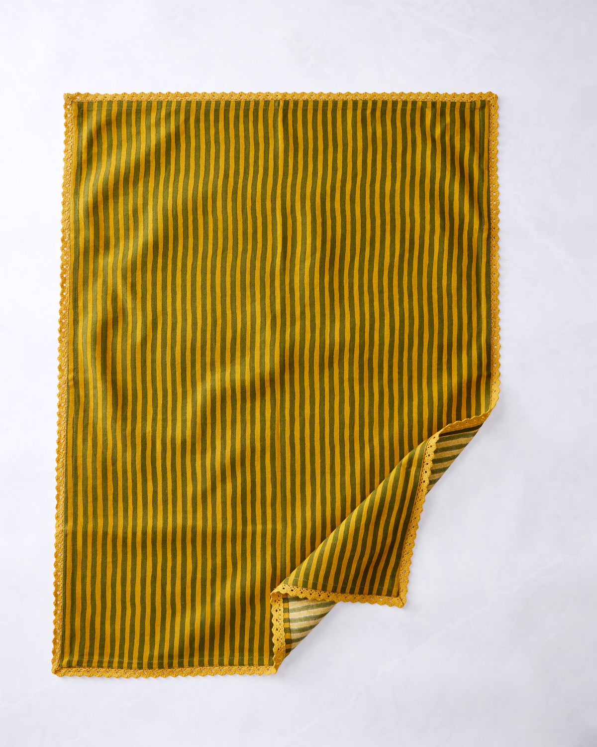 Green and gold vertically striped kitchen towel with scalloped trim and one corner folded back.