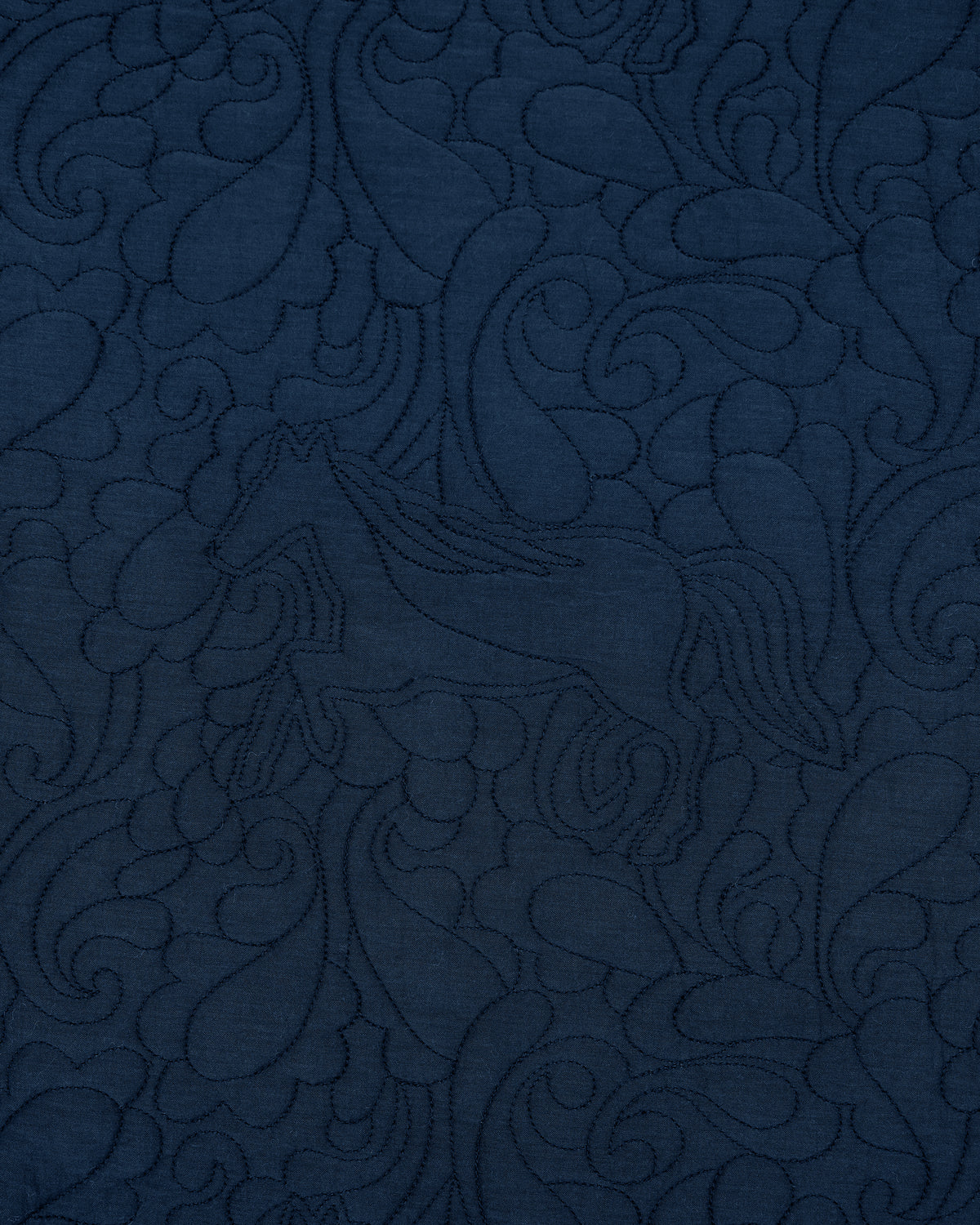 Close-up of dark indigo quilted fabric with an embossed equestrian and paisley pattern.