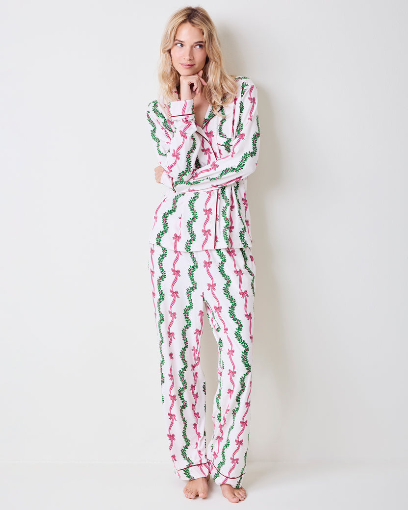 Full-length view of a person wearing the Ribbons & Bows button-down pajama set with pink bow and green garland print.