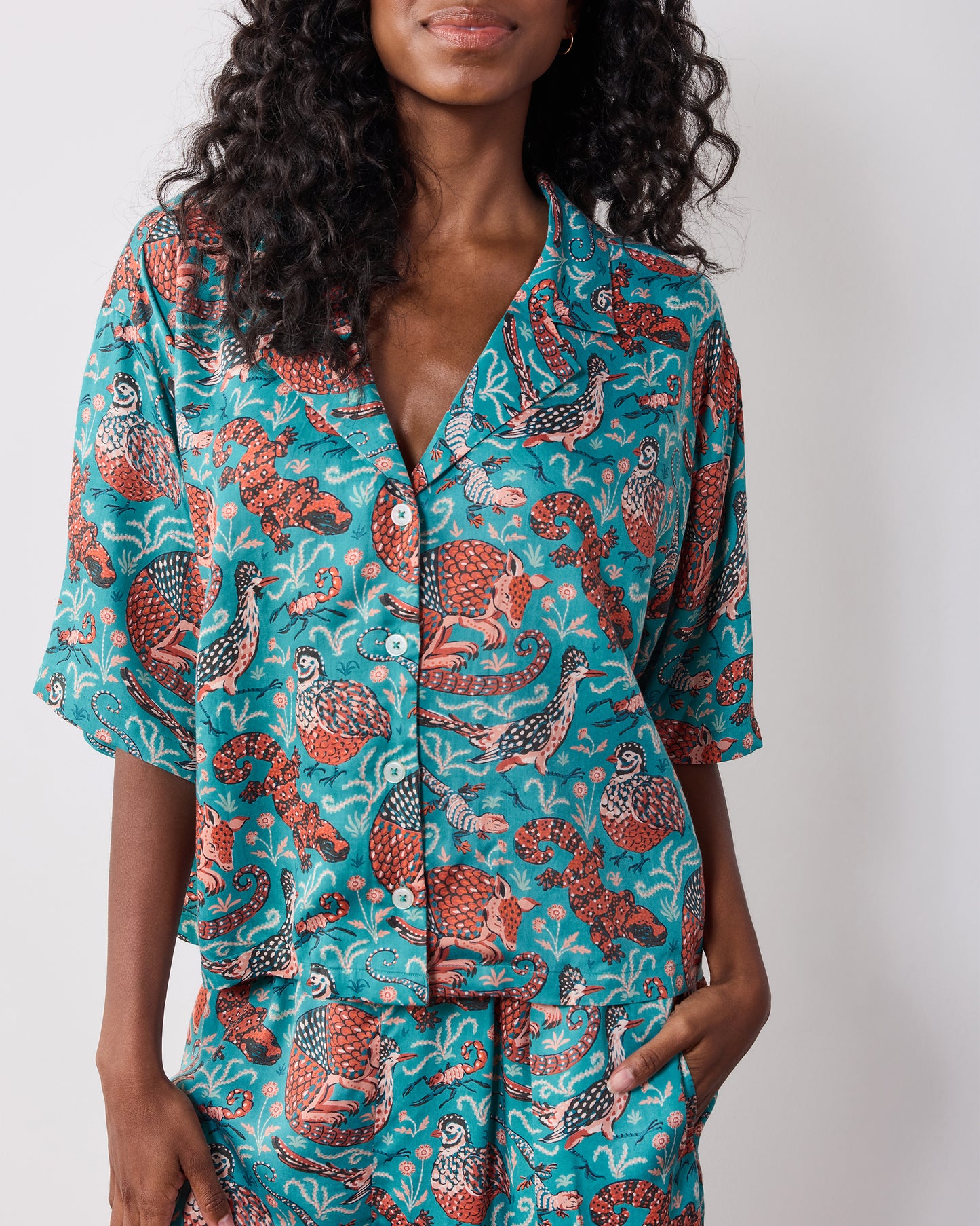 Close view of the teal patterned pajama top with a notched collar and button front.