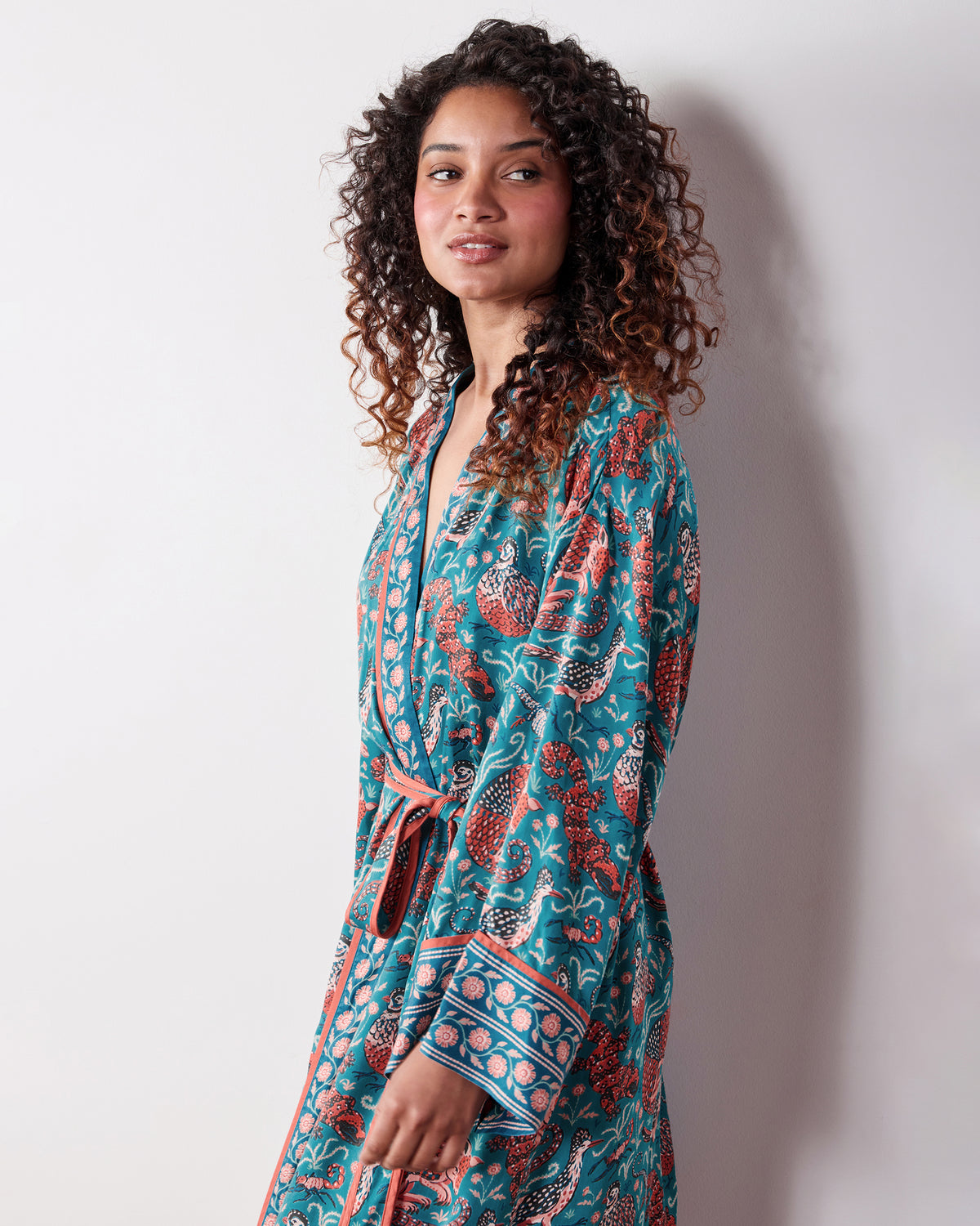 Person wearing the teal Canyon Critters satin robe, showing the patterned robe, internal tie, matching belt, and contrast-trimmed cuffs.