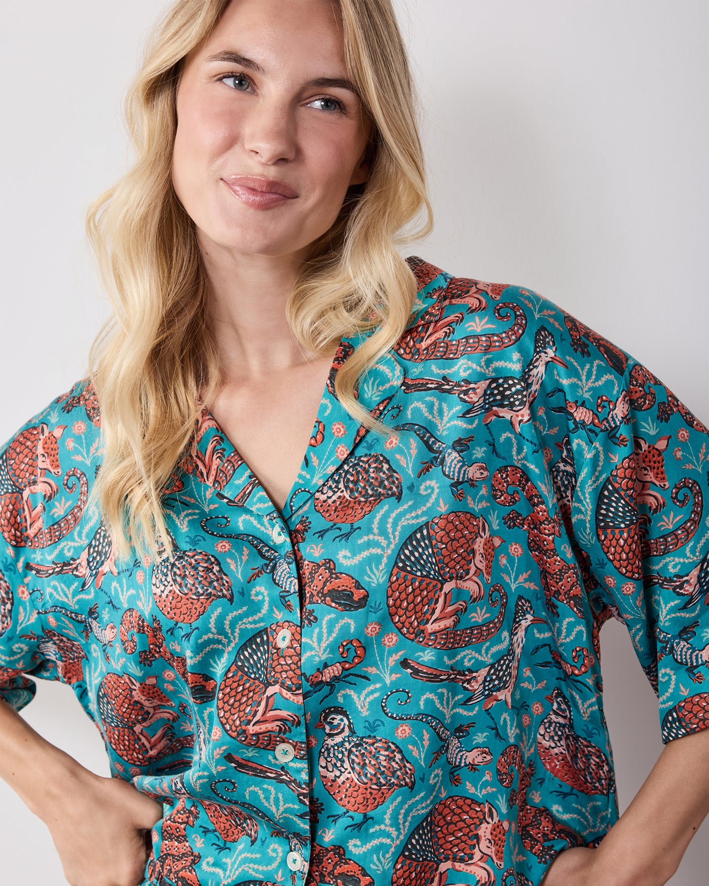 Close view of the teal patterned pajama top with a notched collar and button front.