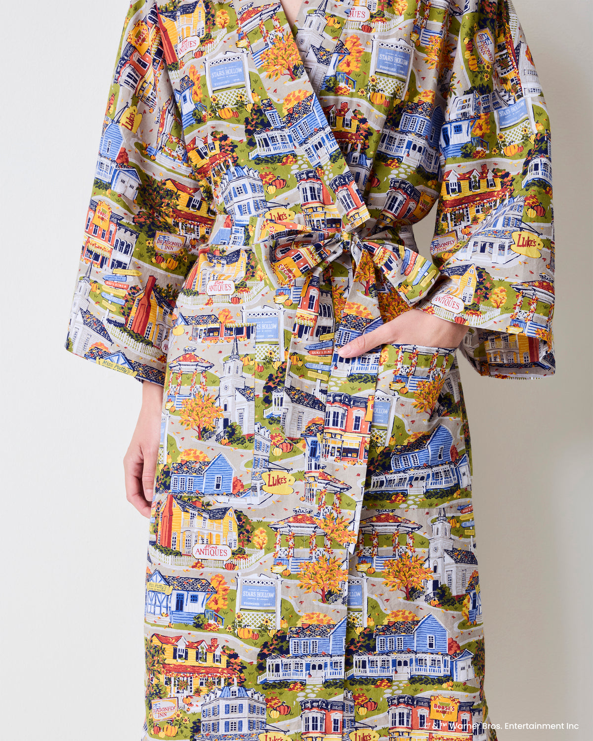 Close-up of the Stars Hollow robe showing the tied sash belt, overlapping front panels, and illustrated town print.