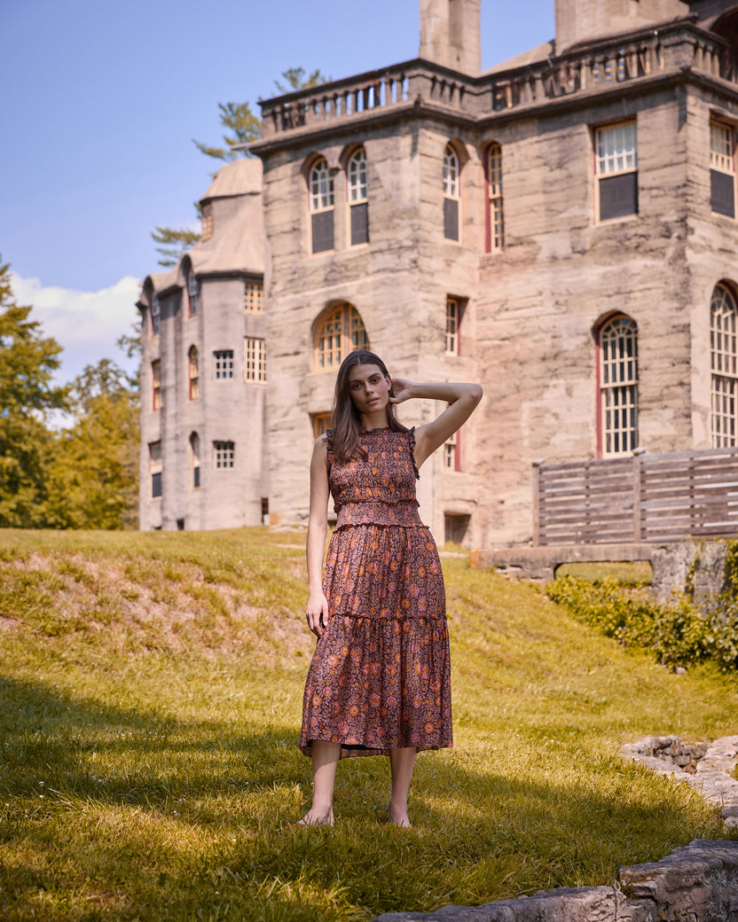 Full-length view of the Sunset Vine Ellis dress, showing its sleeveless bodice, smocked waist, tiered midi skirt, and floral print.
