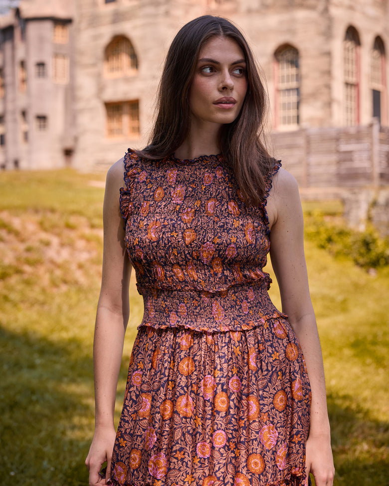 Front close-up of the Sunset Vine Ellis dress, showing the ruffled sleeveless neckline, smocked bodice and waist, and floral print.