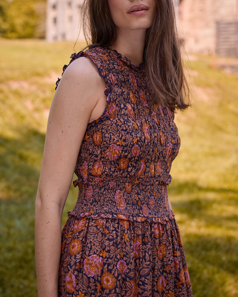Side close-up of the Ellis dress showing the ruffled armhole, smocked bodice and waist, and tiered floral-print skirt.