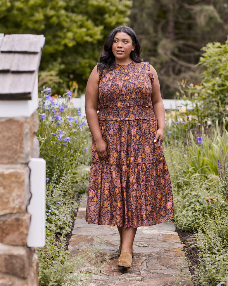 Front full-length view of the Sunset Vine Ellis dress, showing its sleeveless cut, smocked waist, tiered midi skirt, and floral print.