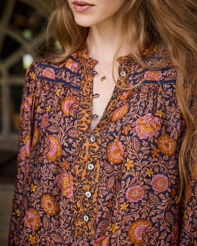 Close-up of the Evelyn blouse neckline and button placket, showing the floral print and pendant necklace.