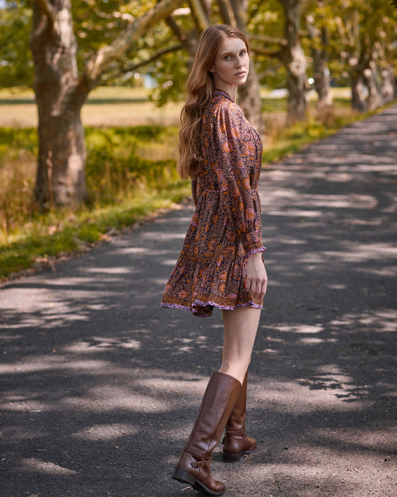 Side and back view of the Sunset Vine Soleil Dress, showing the floral print, long sleeves, tie waist, and tiered skirt.
