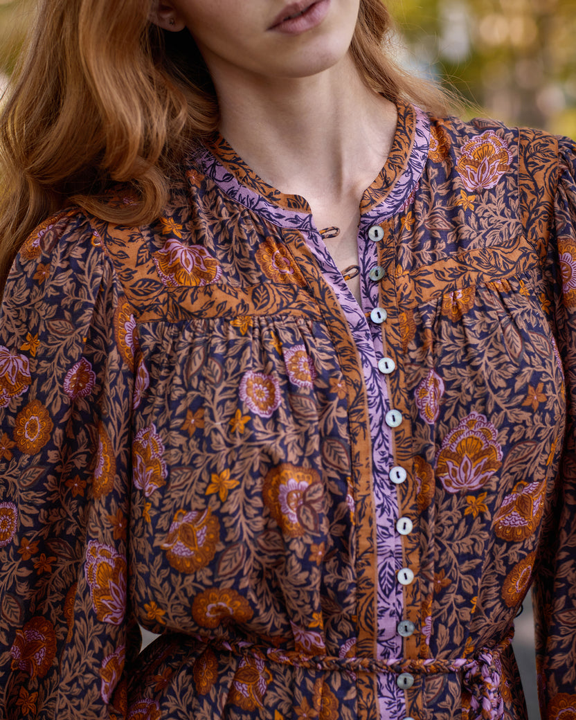 Close-up of the Sunset Vine Soleil Dress showing the floral print, round neckline, button front, and tie waist.
