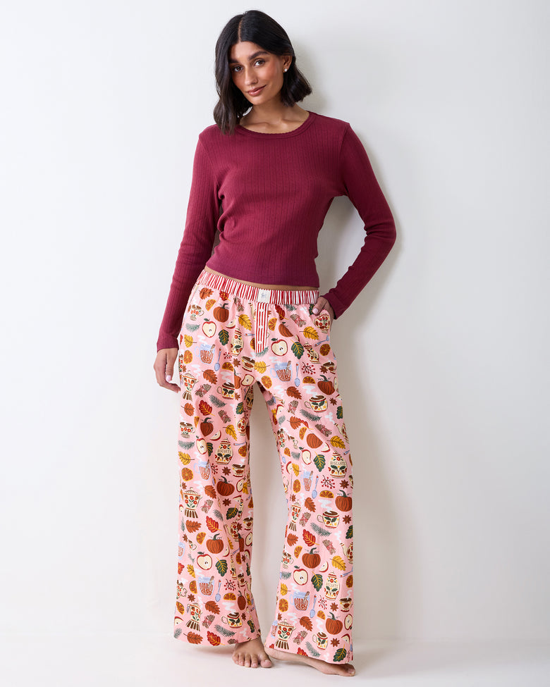 Full-length front view of a person wearing printed wide-leg pajama pants with a striped waistband and button fly.