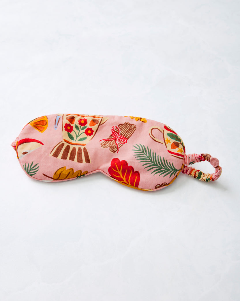 Pink patterned sleep mask shown flat with an attached adjustable strap.