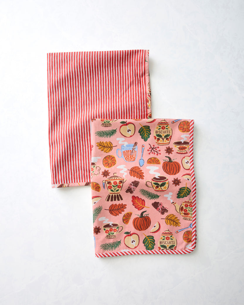 Two tea towels, one with red-and-white vertical stripes and one with a rose-pink autumn tea-and-kitchenware print.