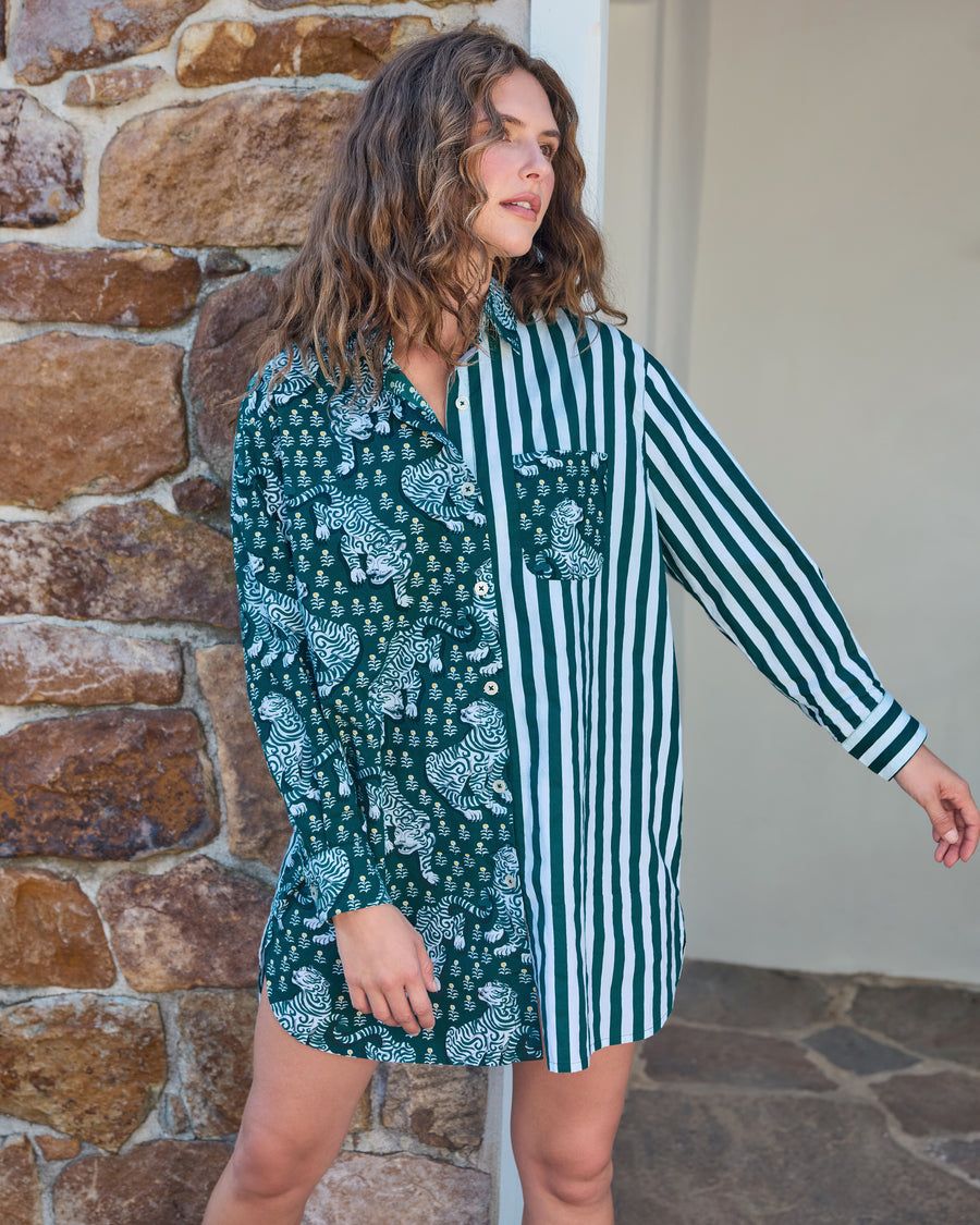 Person wearing a long-sleeved button-down shirt with a green striped print on one side and a green tiger print on the other.