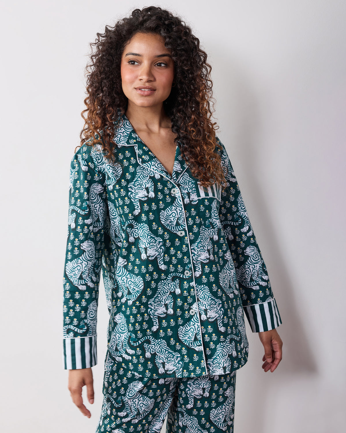 Front view of a green long-sleeve tiger-print pajama set with a button-front top, chest pocket, and striped cuffs.