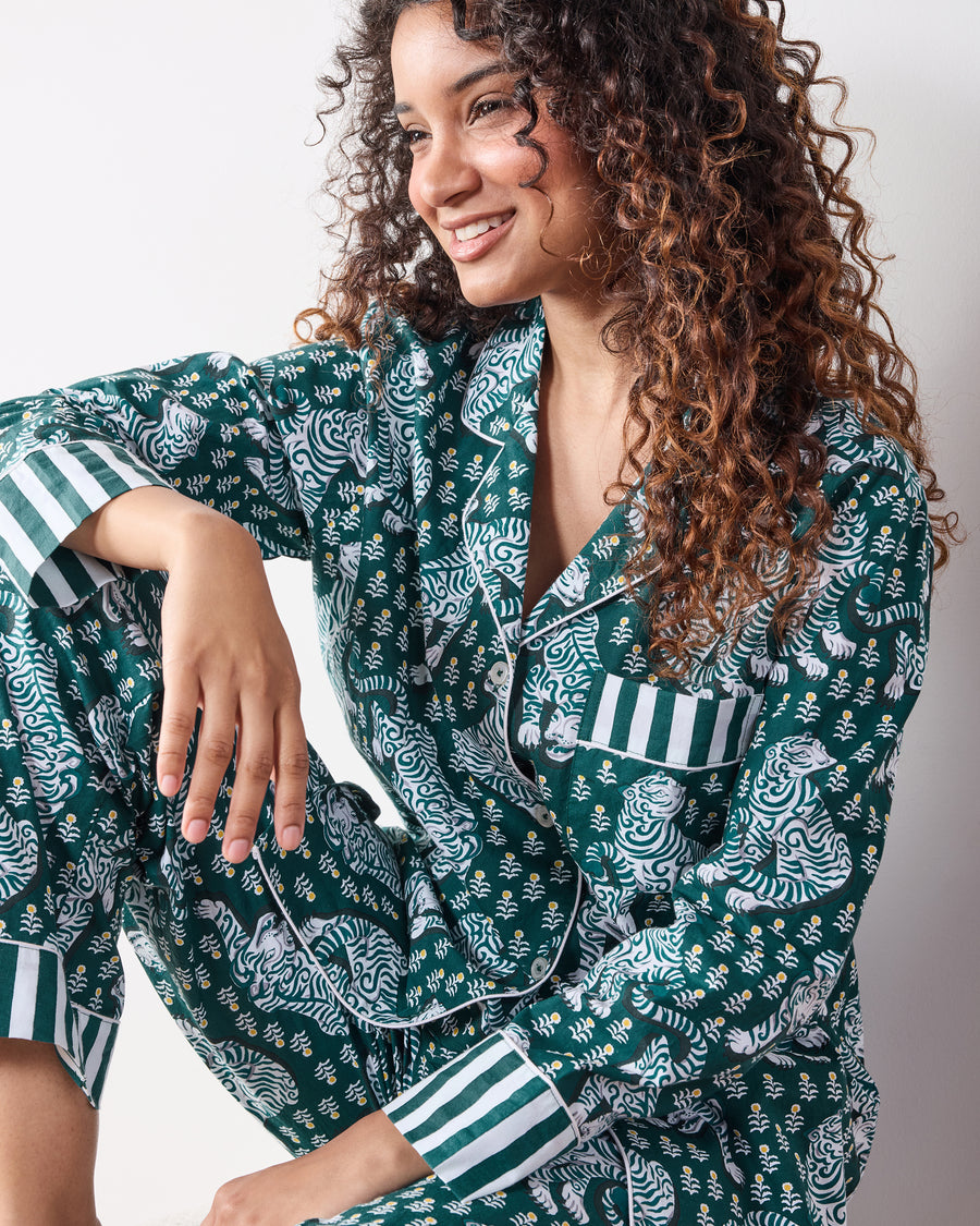 Close-up of a green tiger-print long pajama set showing the button-front collar, chest pocket, and striped cuffs.