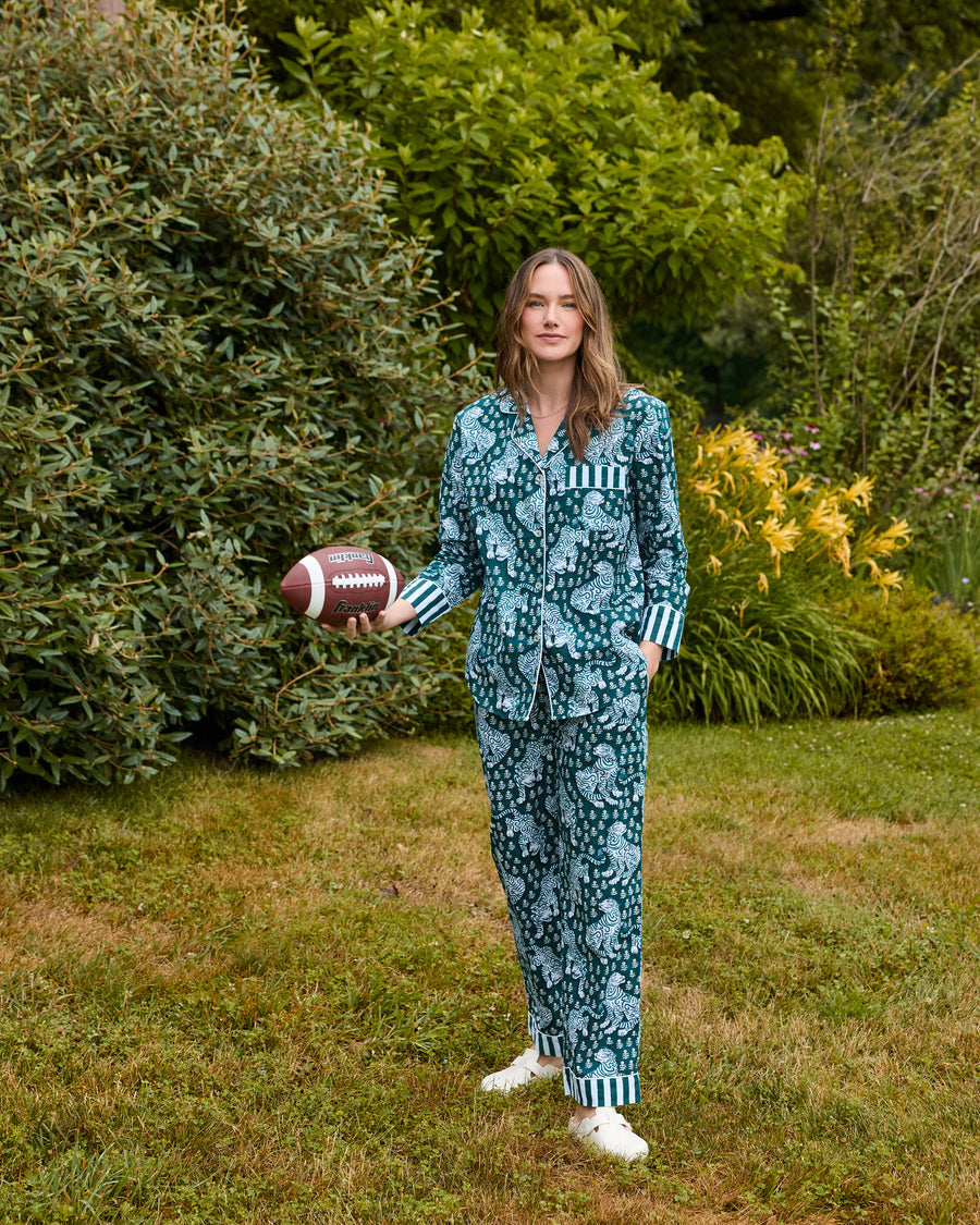 Full-length view of a Game Day Green Tiger Queen long pajama set worn outdoors, with a button-down top, drawstring pants, striped cuffs, and a football.