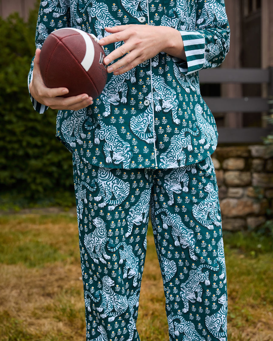 Close-up of the Game Day Green Tiger Queen pajama set showing the button-front top, striped cuff, pocket, tiger print, and drawstring pants while holding a football.