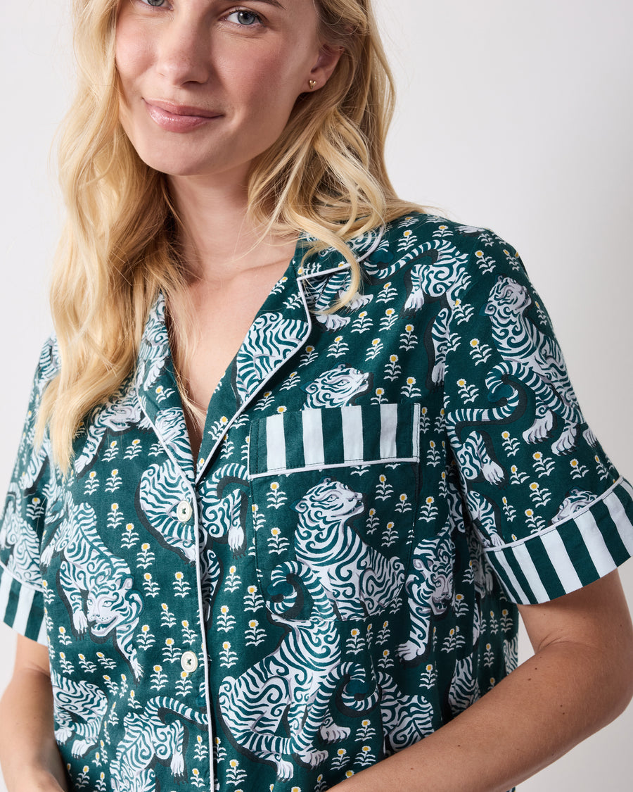Close-up of the green tiger-print pajama top showing the striped chest pocket, piping, buttons, and sleeve cuff.