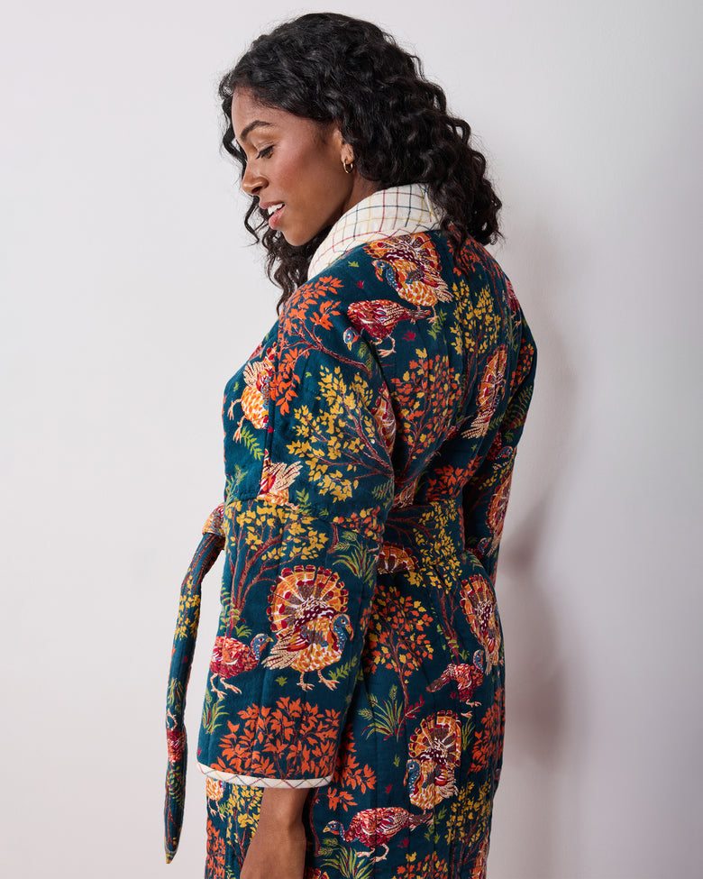 Back three-quarter view of a navy Turkey Trot robe with colorful turkey-and-floral print, plaid collar and cuffs, and waist tie.