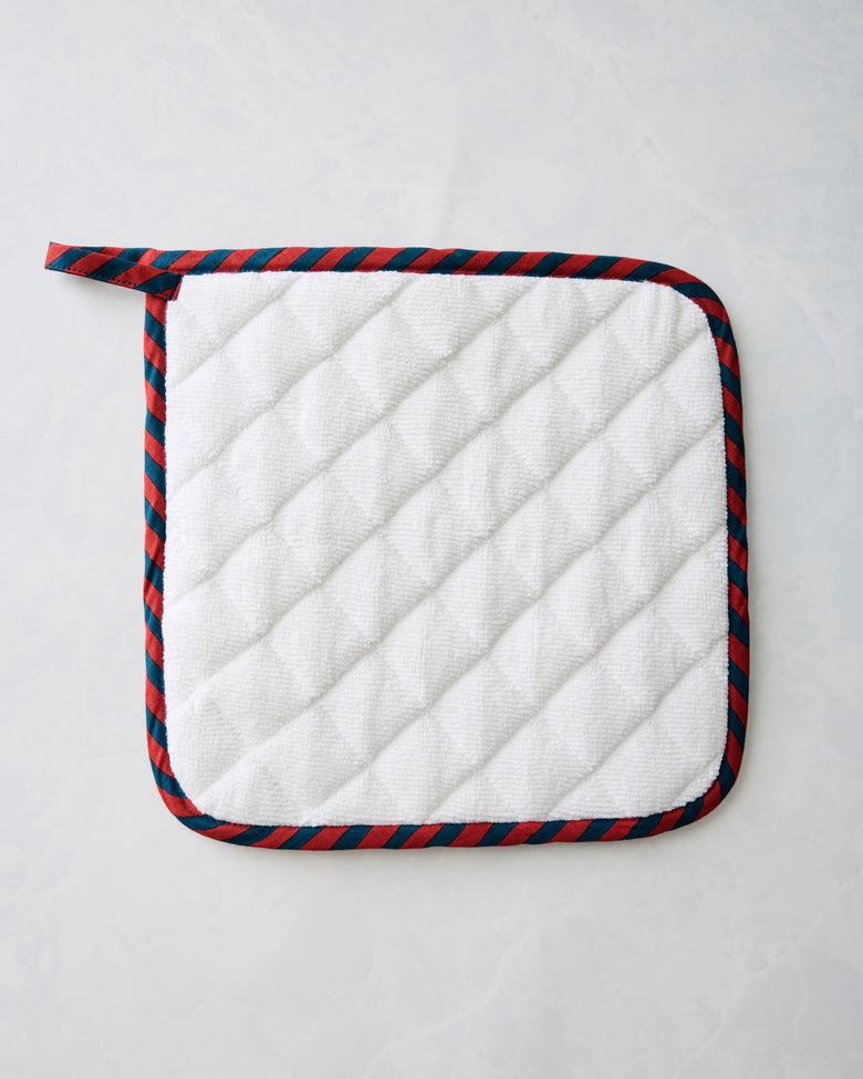 White quilted pot holder with navy-and-red striped binding and hanging loop.