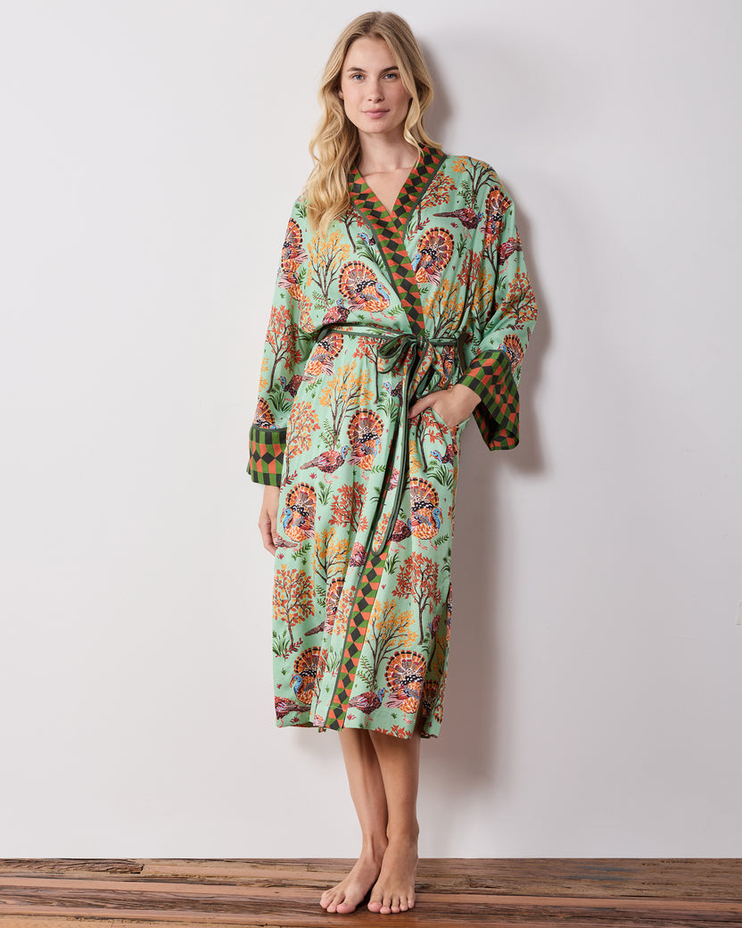 Full front view of a long soft sage Turkey Trot robe with a turkey-and-autumn-tree print, contrasting trim, tied waist, and side pockets.