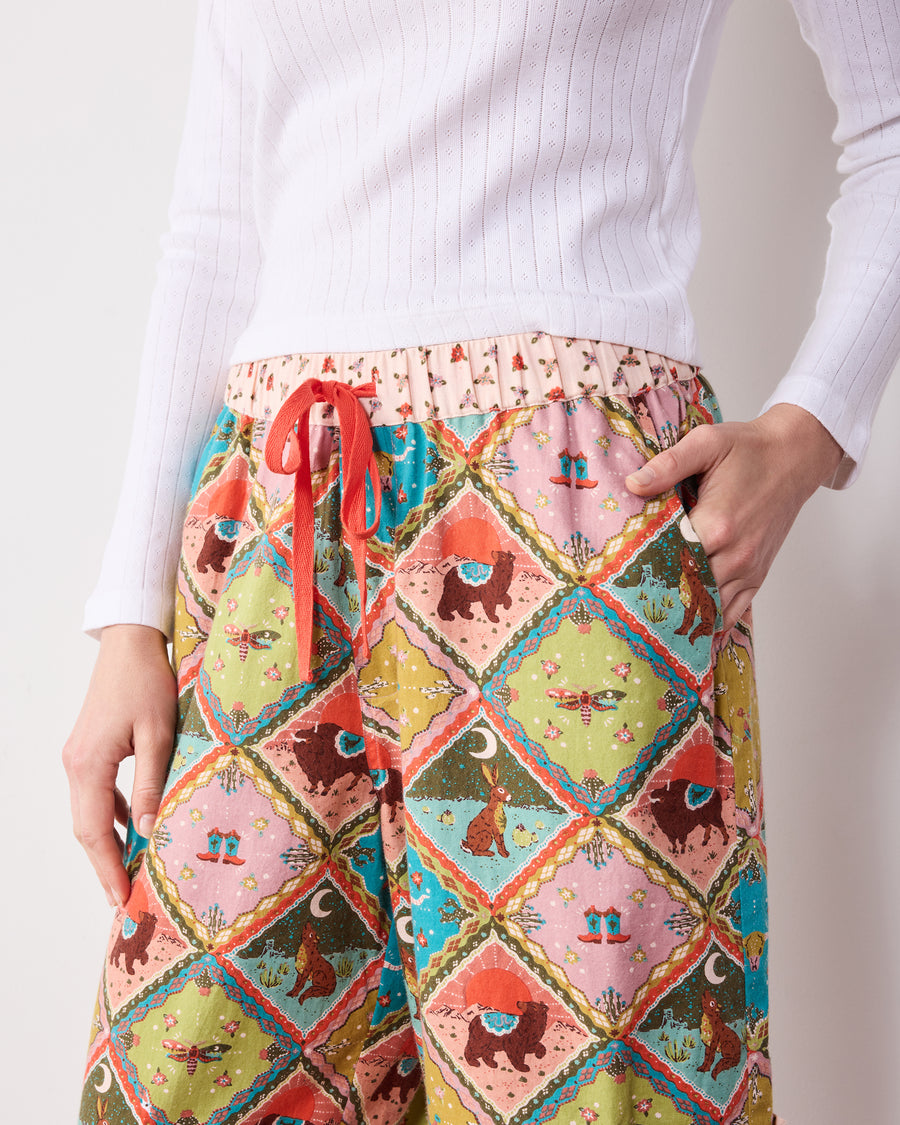 Close view of the patterned pants showing the drawstring waist and side pocket with a contrasting flap.