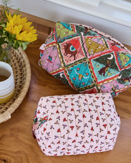 Close view of two quilted oversized pouches showing their colorful patchwork-style and floral prints.