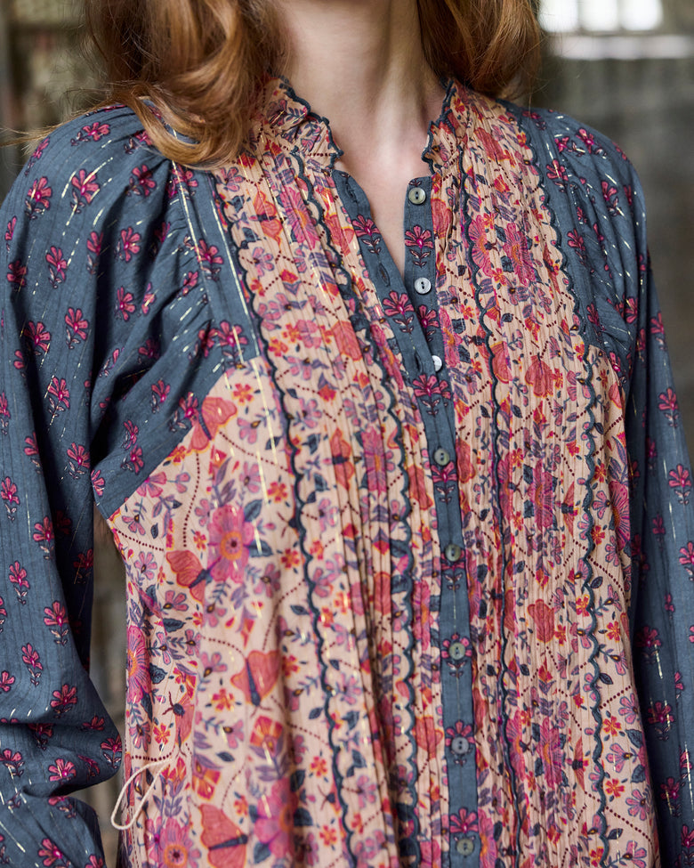 Close-up of the Lauren Dress neckline showing pleated floral panels, buttons, and blue patterned sleeves.