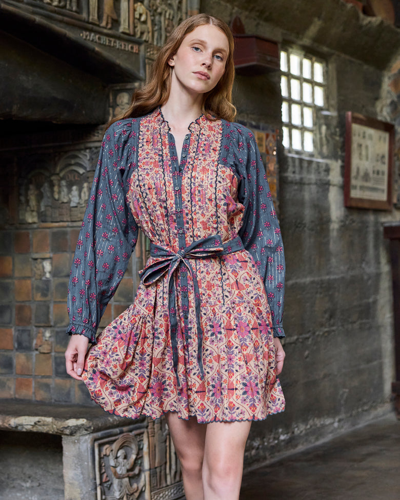 Front view of the Winged Tapestry Lauren dress with a tie belt, floral print, button placket, long sleeves, and scalloped skirt hem.