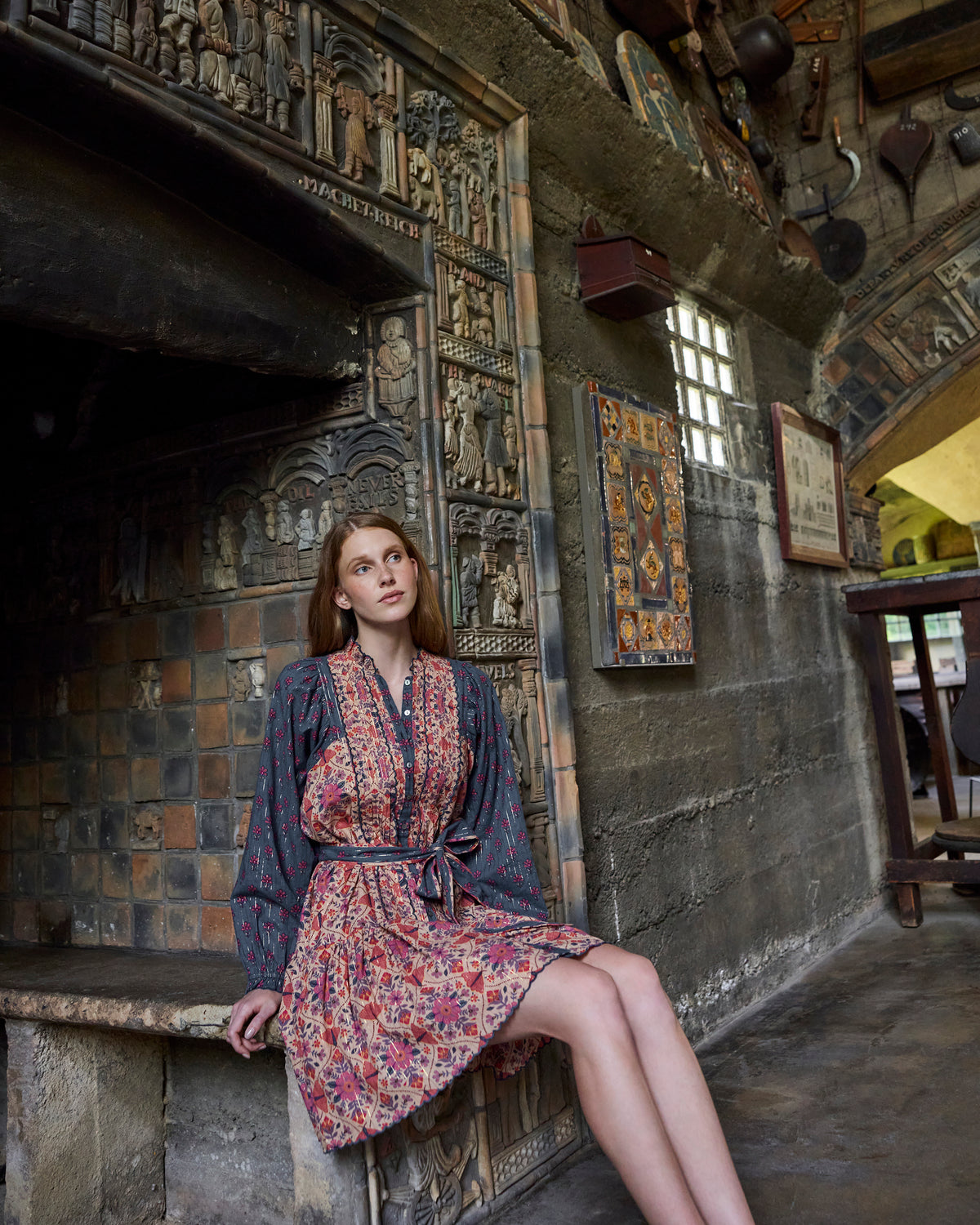 Full-length view of the Winged Tapestry Lauren dress worn with its waist tie, floral print, long sleeves, and scalloped hem.