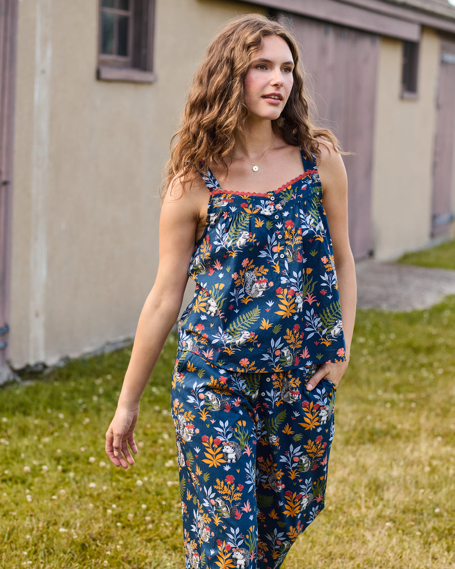 Three-quarter front view of a sleeveless indigo pajama set with a woodland animal and botanical print, loose top, and cropped pants.