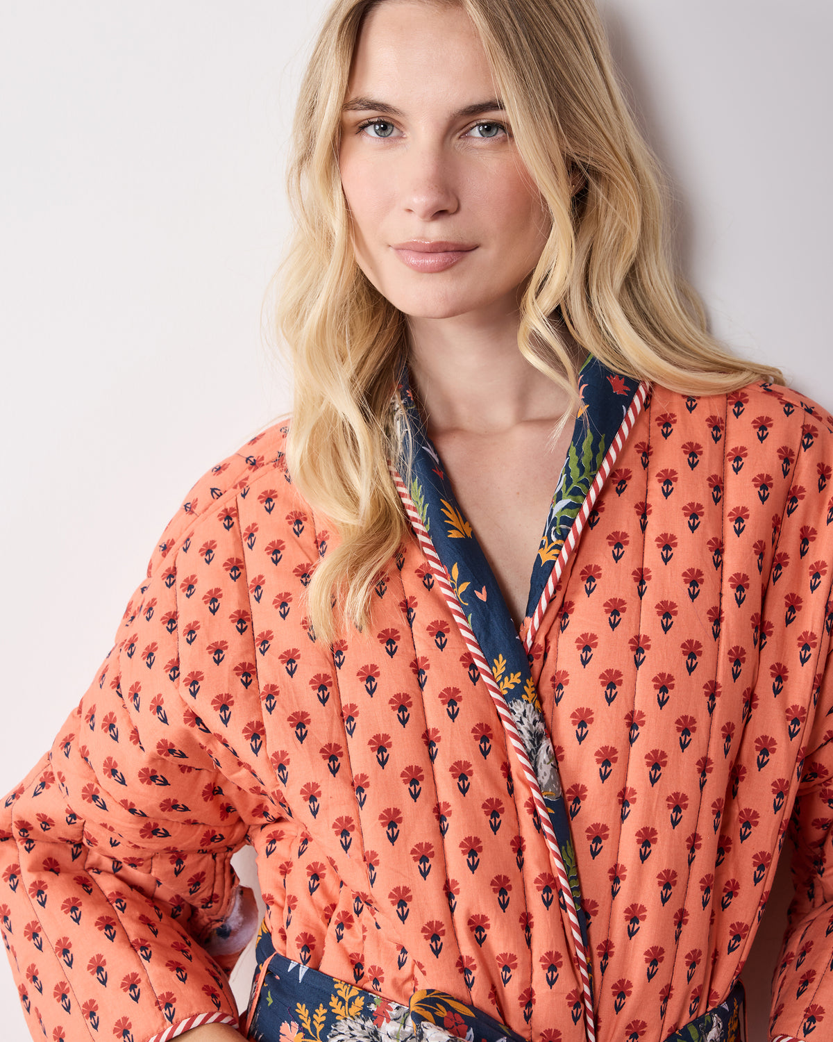 Close-up of the robe’s coral reverse side with a small floral print, contrasting indigo collar, and striped trim.