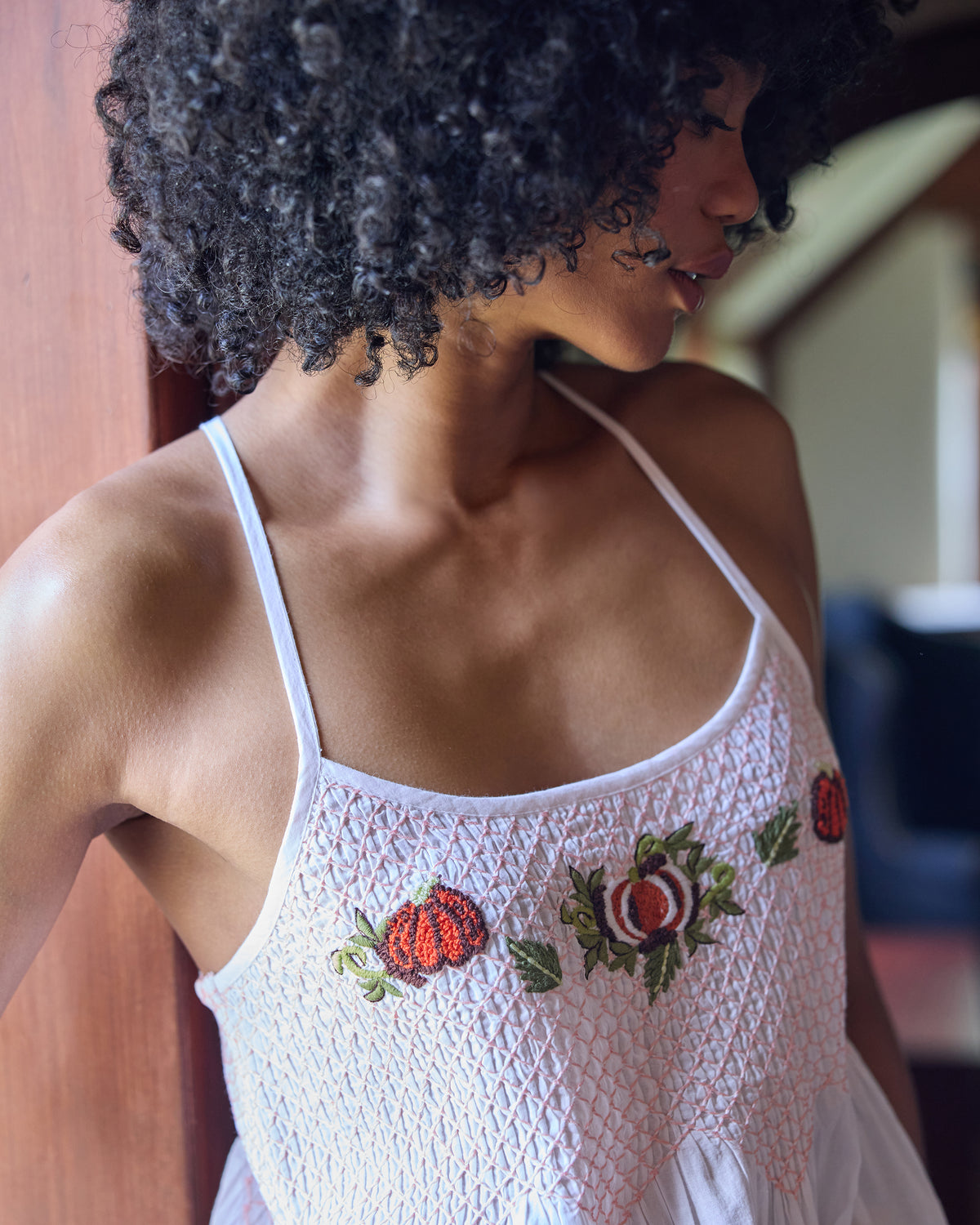 Close-up of the Naya nightie bodice showing smocked stitching, thin straps, and embroidered pumpkins with flowers.