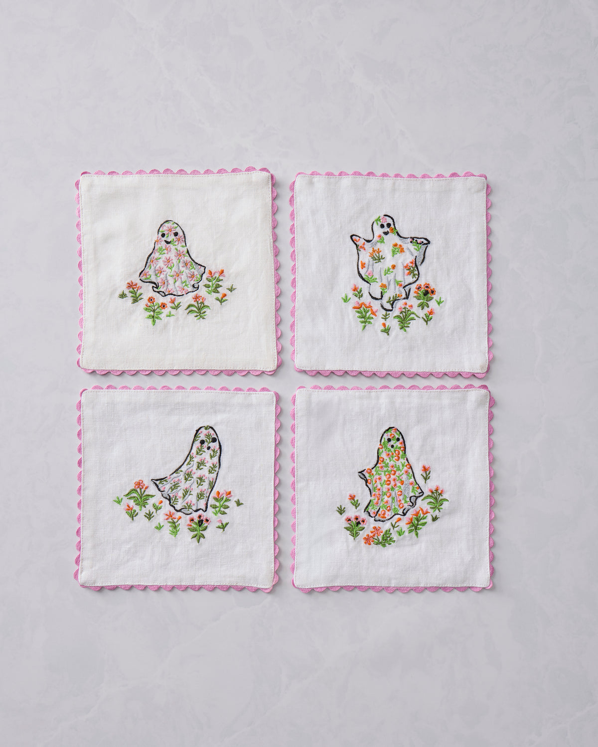 Set of four white Gardening Ghosts cocktail napkins with pink scalloped edges and embroidered ghosts among flowers