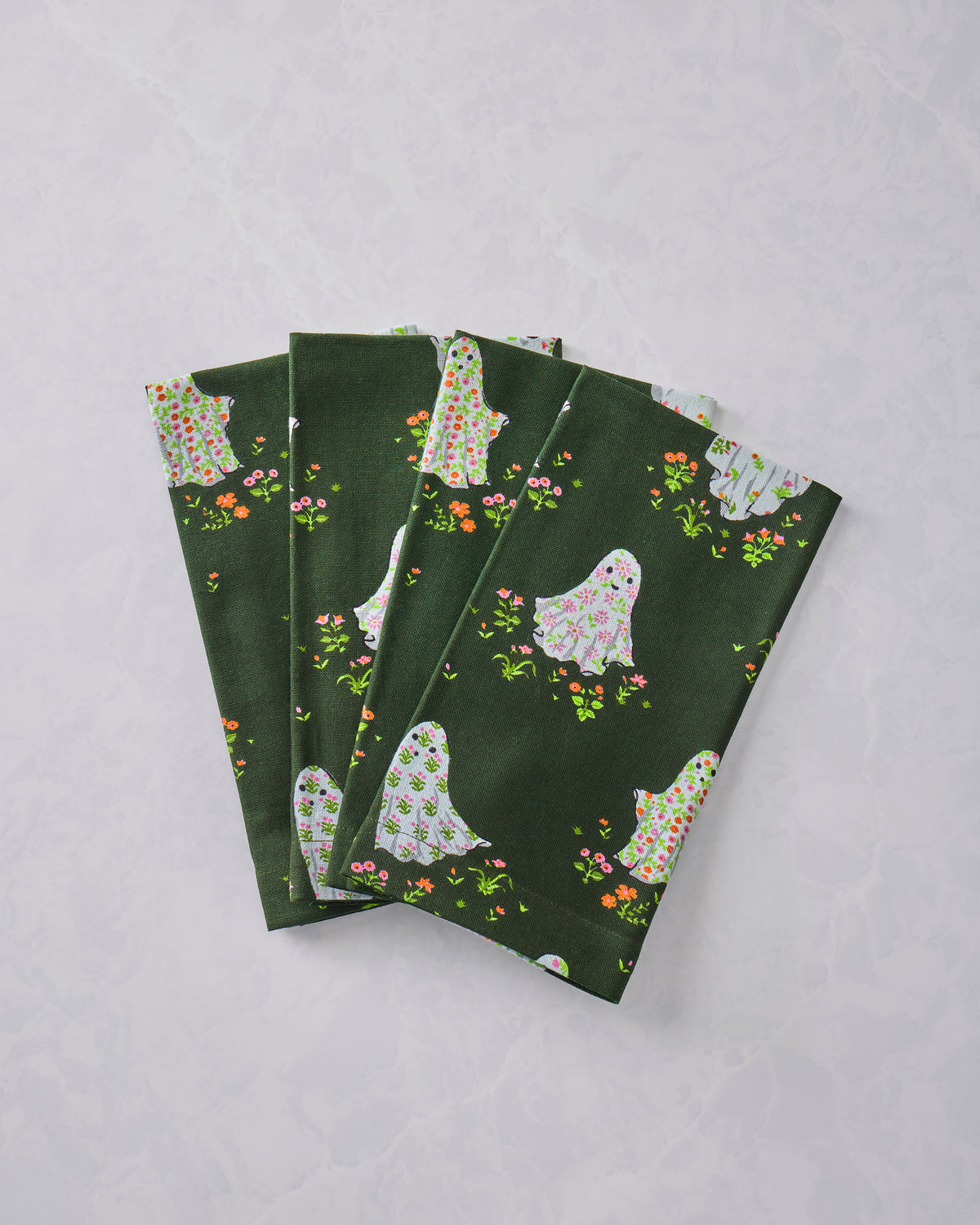 Four folded dark green dinner napkins printed with floral ghosts and scattered flowers.