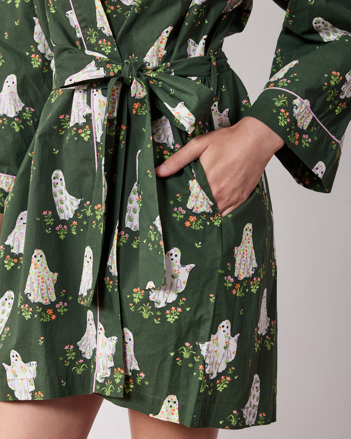 Close view of the Gardening Ghosts robe showing the tied belt, side pocket, piping, and ghost-and-flower print.