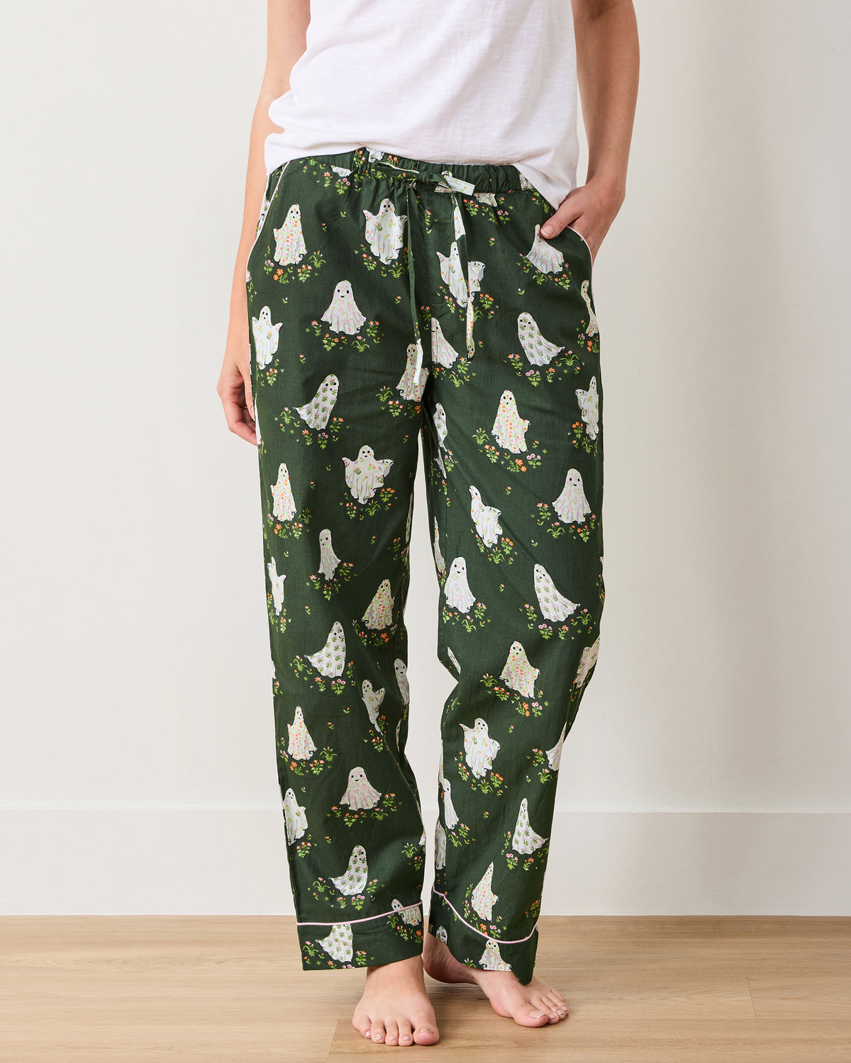 Front view of Overgrown Moss Gardening Ghosts pajama pants, showing the relaxed legs, side pockets, drawstring waist, ghost-and-flower print, and cuff trim.