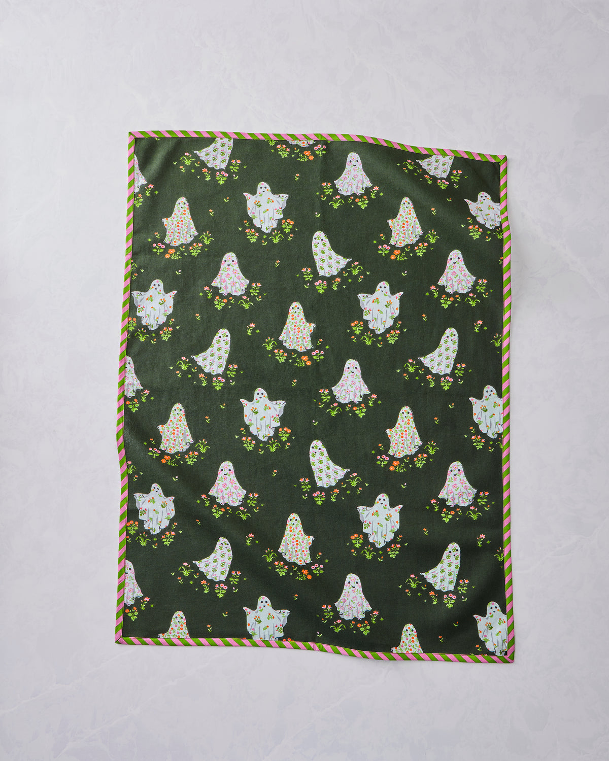 Tea towel laid flat with an all-over dark green print of floral ghosts and scattered flowers, finished with a pink-and-green striped border.