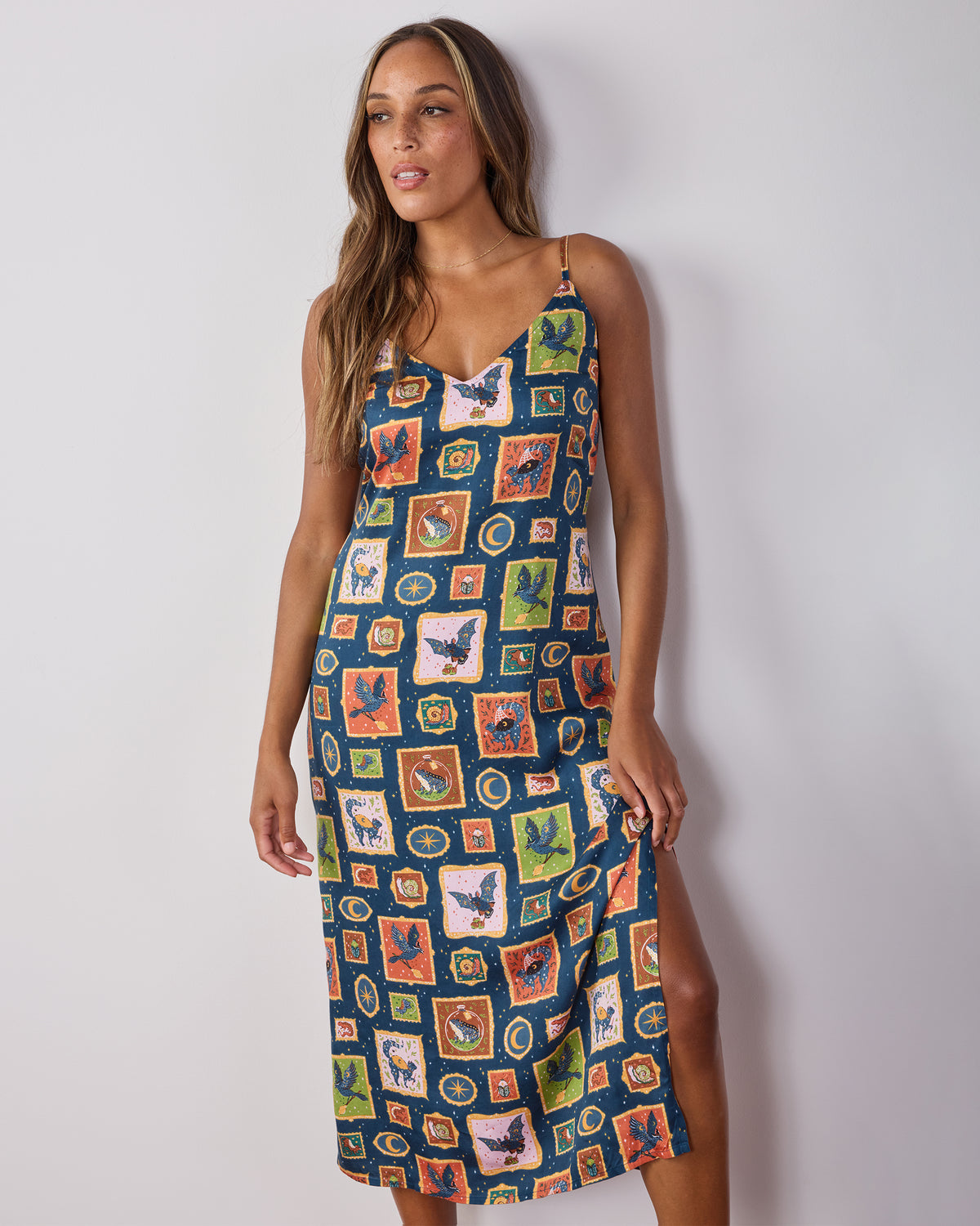 Front angled view of the Midnight Gallery Eco Satin nightie showing its V-neckline, adjustable straps, midi length, side slit, and printed design.