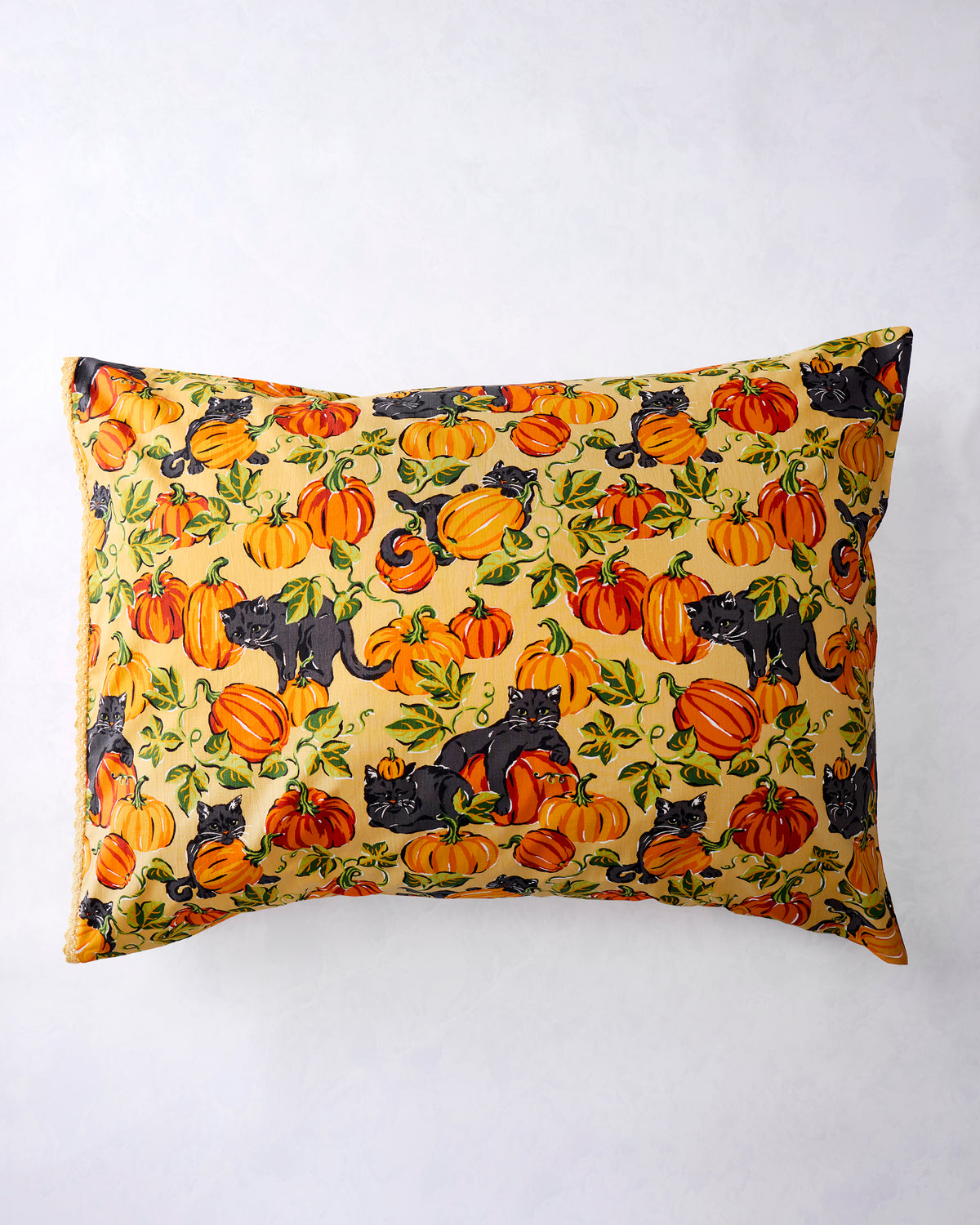 Pumpkin Prowl pillowcase with black cats and orange pumpkins on a salted-caramel background, shown flat with lace trim along the opening.