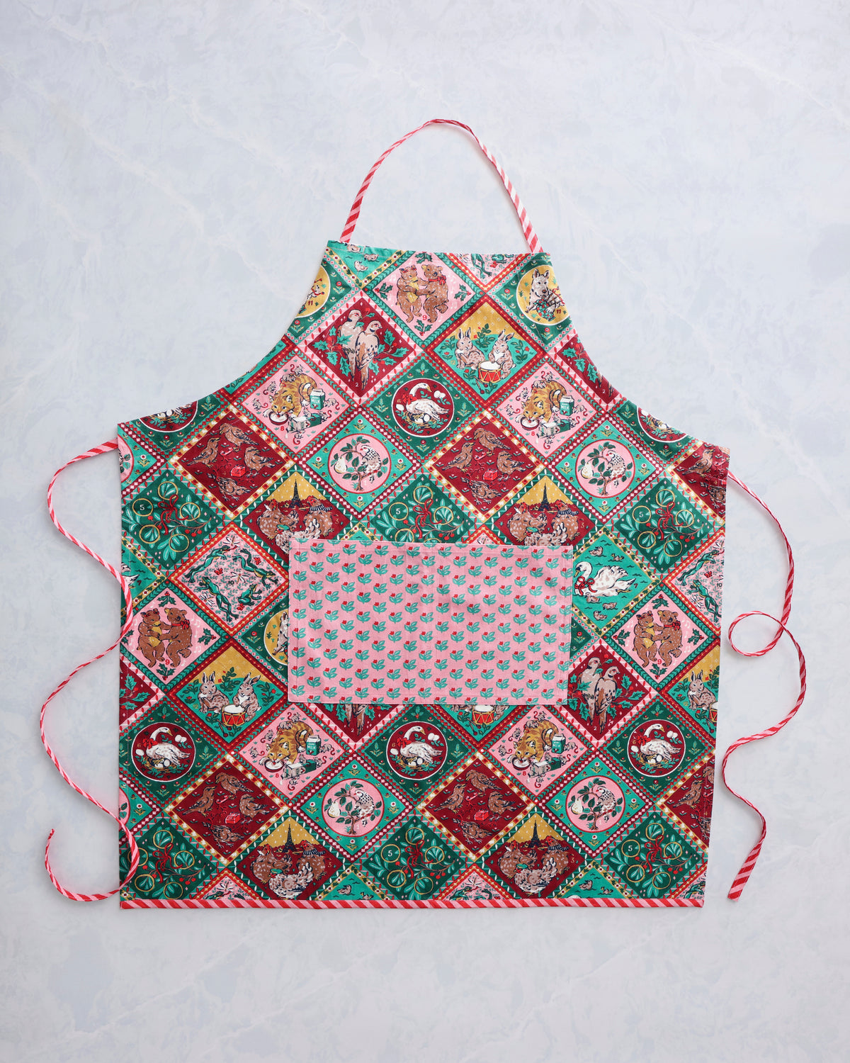 Flat lay of a Christmas-patterned apron with a pink floral pocket and red-and-white trim.