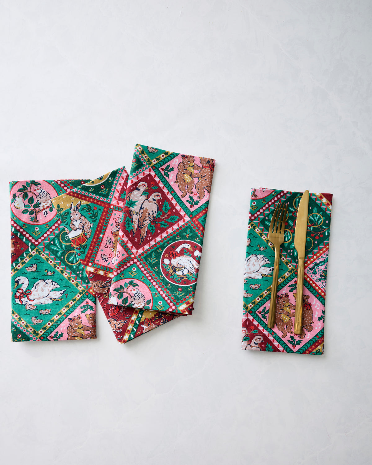 Four printed dinner napkins displayed separately, with one napkin holding a fork and knife.
